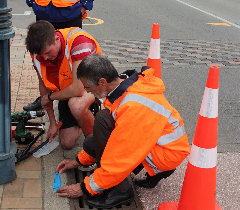 Picture of someone attaching a Blue Fish to a Timaru Storm Drain