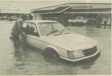 a man next to a white sedan which has floodwaters